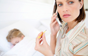 concerned mother holding a thermometer and making a phone call