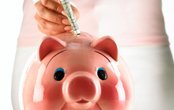 woman putting cash in a pink piggy bank