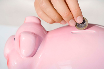 close up of a hand placing change in a piggy bank