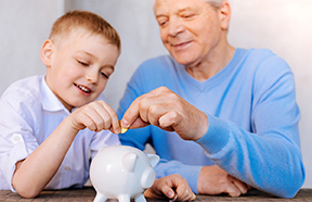 grandpa and grandson putting money in a piggy bank
