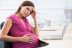 a pregnant woman sitting at her desk