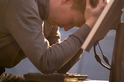 man sitting next to a computer with his head in his hands