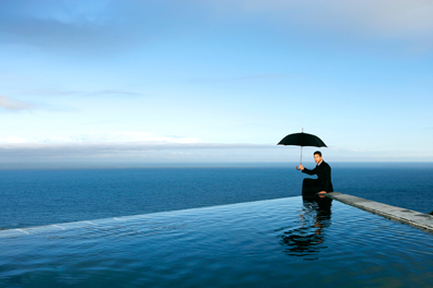 business man sitting under an umbrella surrounded by water